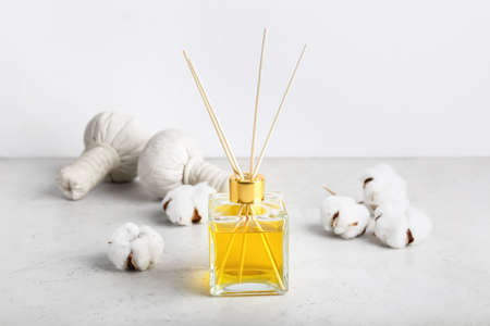 Reed diffuser with cotton flowers on table against white background