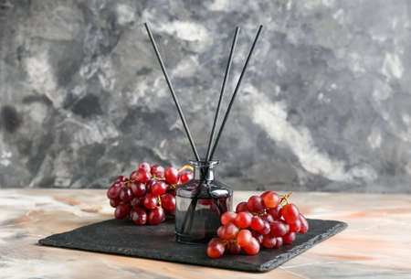 Reed diffuser with grapes on grunge background