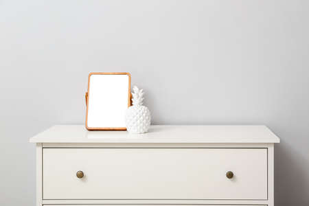Mirror and decor on chest of drawers near light wallの写真素材
