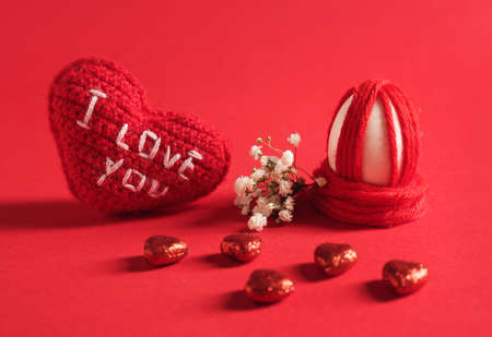 Creative Easter egg, heart and candies on color background