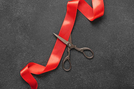 Shiny red ribbon and scissors on dark backgroundの写真素材