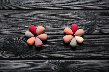 Composition with makeup sponges on dark wooden background