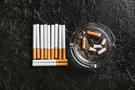 Ash tray and cigarettes on dark background
