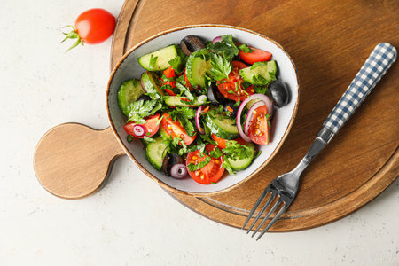Bowl of fresh salad with vegetables on light backgroundの写真素材