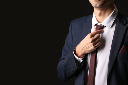 Young man in stylish suit on dark backgroundの写真素材