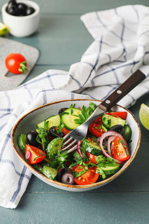 Bowl of fresh salad with vegetables on color wooden backgroundの写真素材