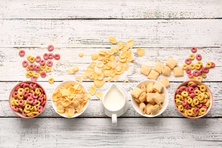 Composition with different cereals and milk on light wooden background