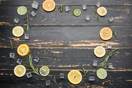 Frame made of healthy citrus fruits and ice cubes on dark wooden backgroundの写真素材