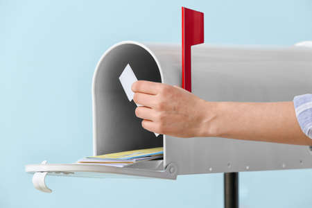 Woman getting letter from box on color backgroundの写真素材