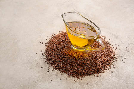 Gravy boat with flax oil and seeds on grunge backgroundの写真素材