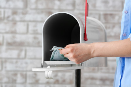 Woman getting money from box on brick backgroundの写真素材