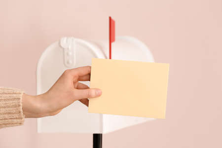 Woman with letter near mail box on light backgroundの写真素材