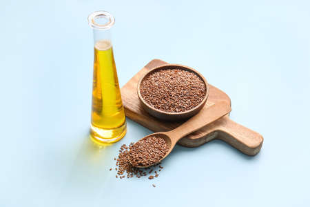 Bottle with flax oil and seeds on color backgroundの写真素材