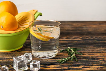Glass of healthy lemonade and squeezer on wooden backgroundの写真素材