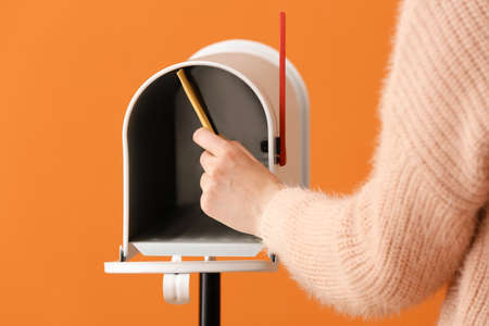 Woman getting letter from box on color backgroundの写真素材