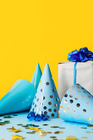 Gift with party cones and confetti on color backgroundの写真素材