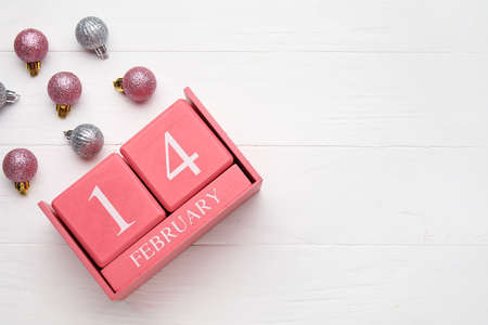 Calendar with date of Valentines Day and Christmas balls on light wooden backgroundの写真素材