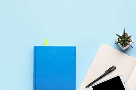 Book with bookmark and mobile phone on color background