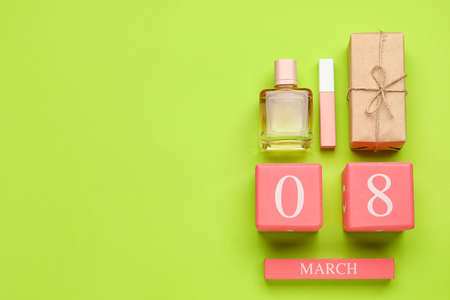 Calendar with date of International Women's Day, gift box, lipstick and bottle of perfume on green...