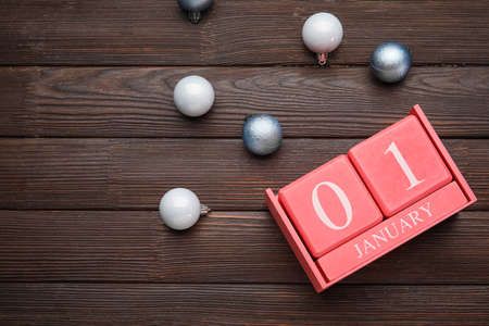 Calendar with date of New year and Christmas balls on wooden background