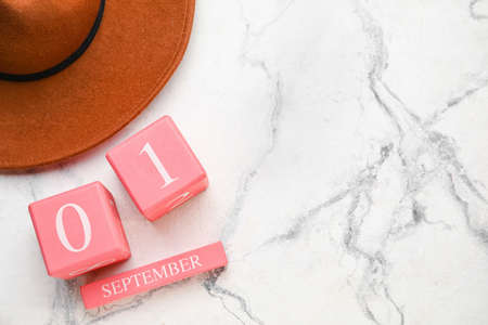 Calendar with date of September 1 and hat on light background