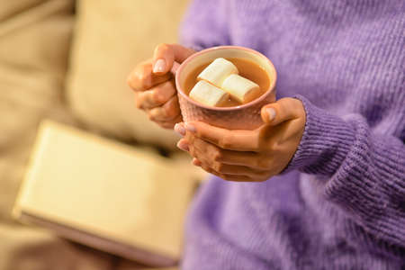 Beautiful young woman drinking hot chocolate at home, closeup