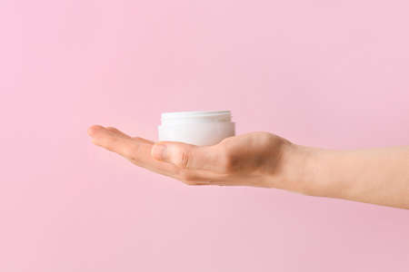 Woman with jar of cosmetic product on color background