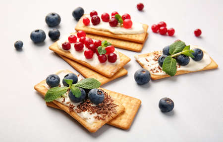 Tasty crackers with berries on gray background