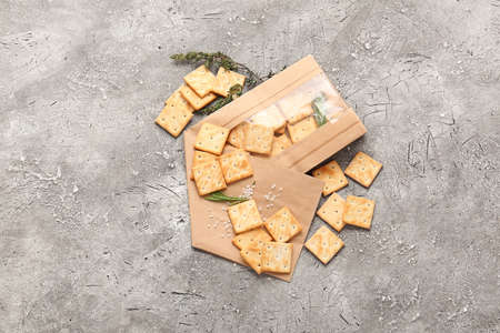 Paper bag with tasty crackers on grunge background