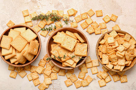 Bowls with tasty crackers on grunge background