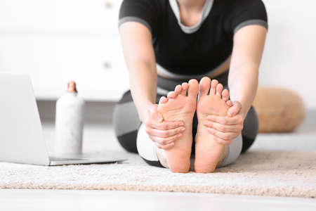 Sporty young woman with laptop practicing yoga at home during lockdownの写真素材