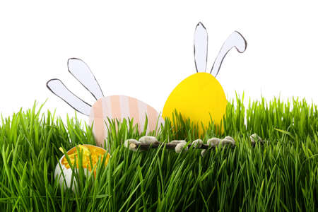 Paper Easter eggs in grass on white background