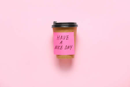 Takeaway cup for coffee and sticker note with text HAVE A NICE DAY on color backgroundの写真素材
