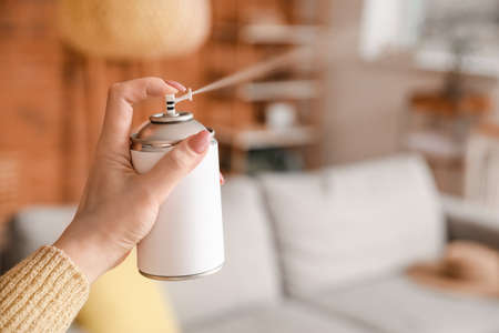 Young woman with air freshener at homeの写真素材