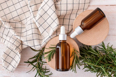 Composition with bottles of essential oil and fresh rosemary on light wooden backgroundの写真素材