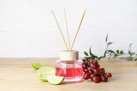 Reed diffuser with lime and grapes on light background