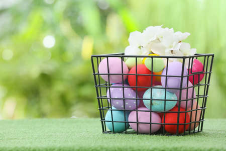 Basket with beautiful Easter eggs on grass outdoors