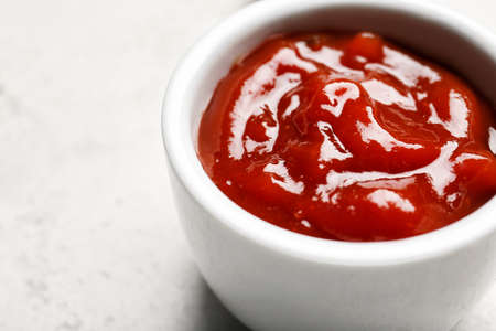 Bowl with tasty barbecue sauce on light background