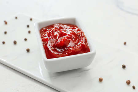Bowl with tasty barbecue sauce on light background
