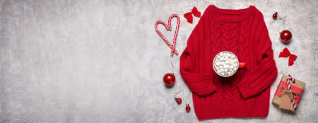 Children's sweater with Christmas gift and cup of hot chocolate on grunge background with space for textの写真素材
