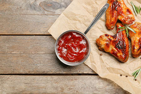 Chicken wings and pot with barbecue sauce on wooden backgroundの写真素材