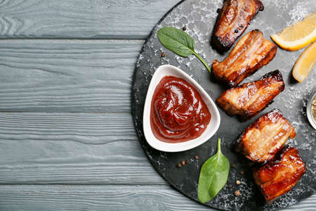 Bowl with tasty barbecue sauce and roasted pork on dark wooden backgroundの写真素材