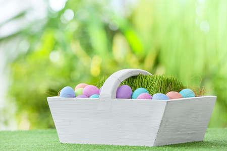 Basket with beautiful Easter eggs on grass outdoors
