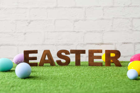 Beautiful composition with Easter eggs on grass against light background