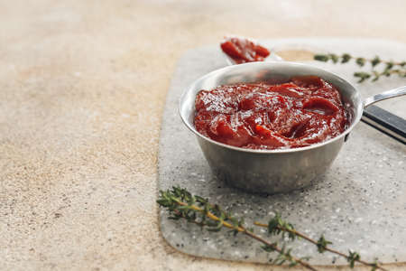 Pot and spoon with tasty barbecue sauce on light background