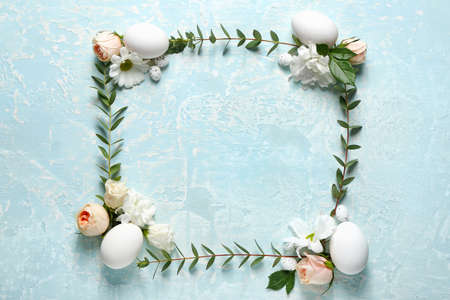Frame made of Easter eggs and spring flowers on light background
