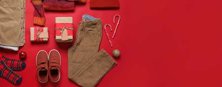 Set of children's clothes with Christmas gifts on color background with space for text