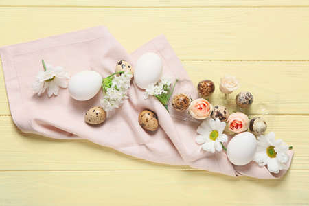 Composition with Easter eggs and spring flowers on color wooden background