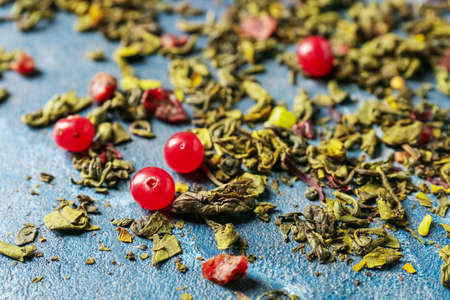 Dry green tea with red currant on color backgroundの写真素材