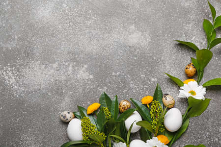 Composition with Easter eggs and spring flowers on gray background